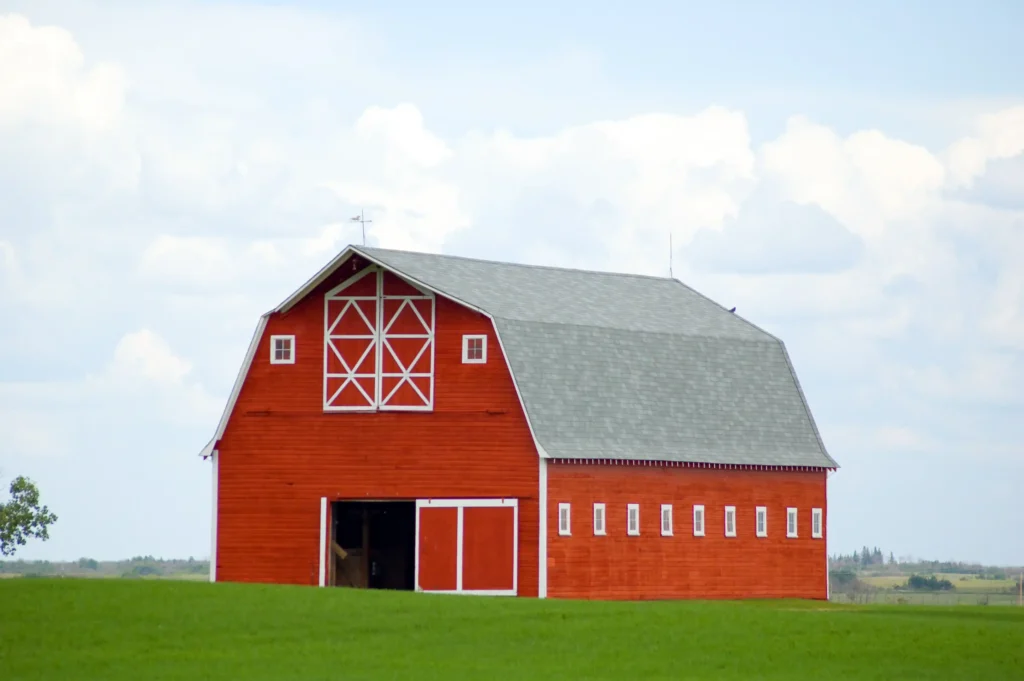 Large red barn with white trim and gray roof on a green grassy field in Orlando, FL